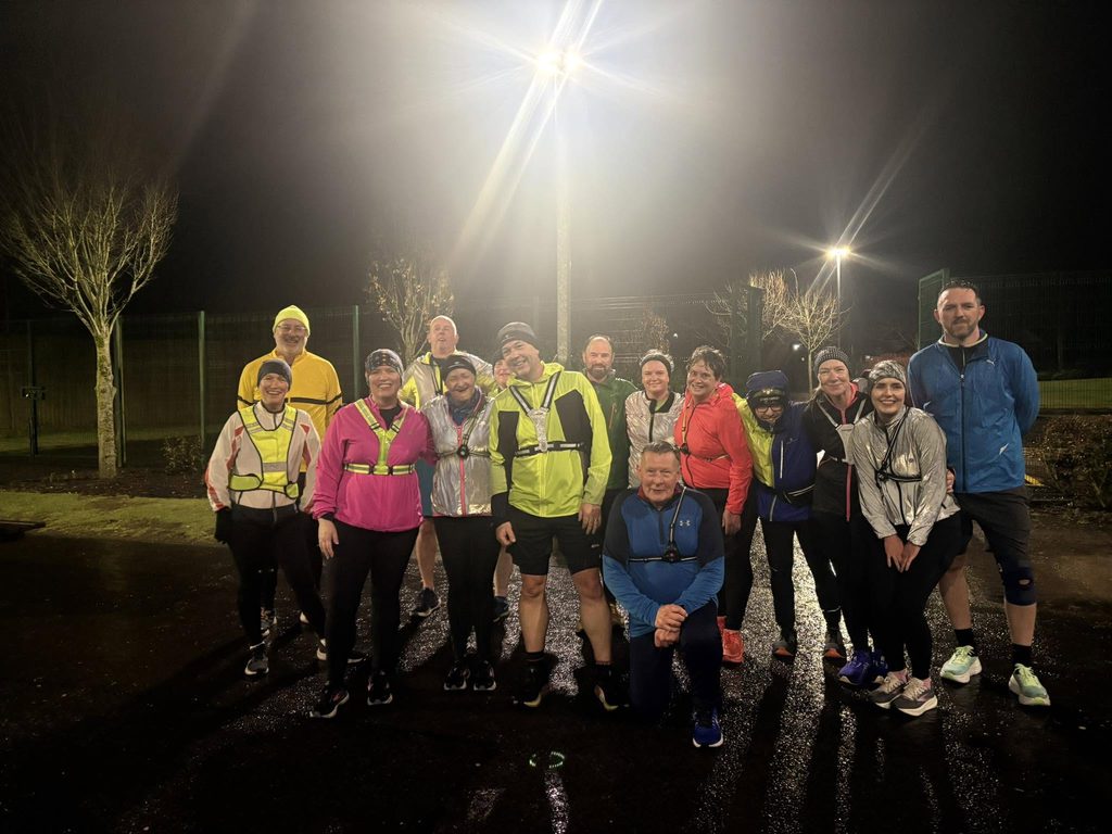 Group of runners in high vis clothing, trees and street lights in the background