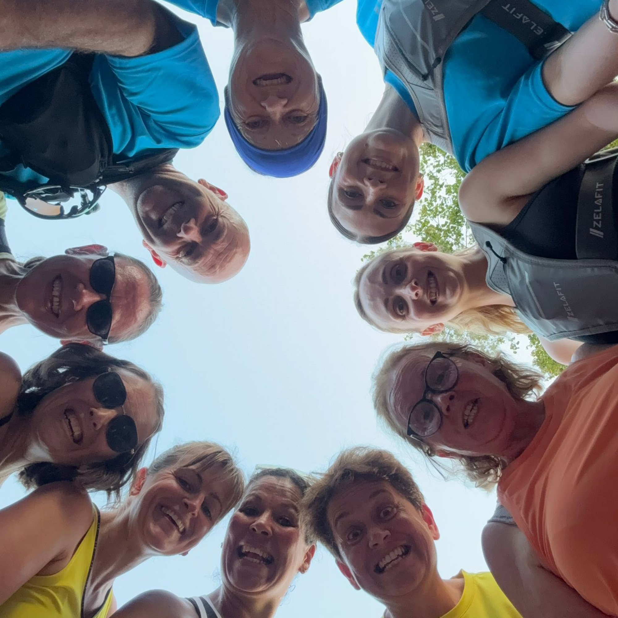 Group of runners standing in a circle looking down towards the camera