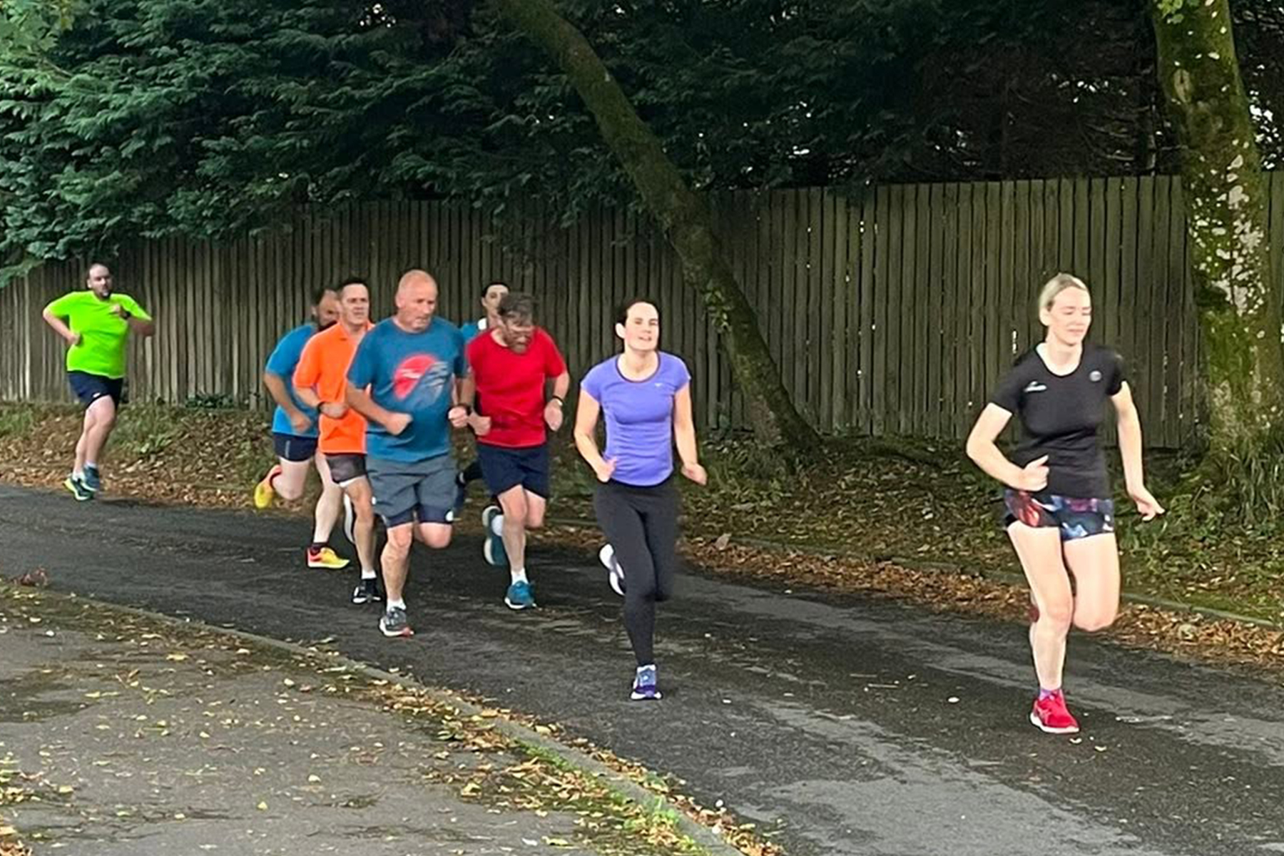 Group of male and female runners running on a road